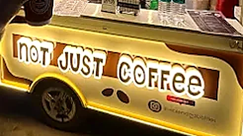 The Not Just Coffee sign glowing along the side of the cart